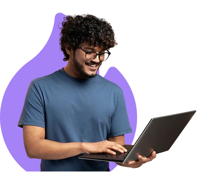 Un jeune homme souriant travaille sur son ordinateur portable